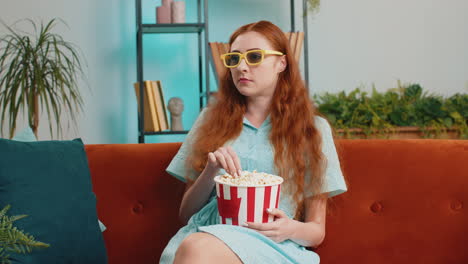 Frau-Sitzt-Auf-Der-Couch,-Isst-Popcorn-Und-Schaut-Zu-Hause-Einen-Interessanten-3D-Fernsehfilm-Oder-Ein-Sportspiel-Online