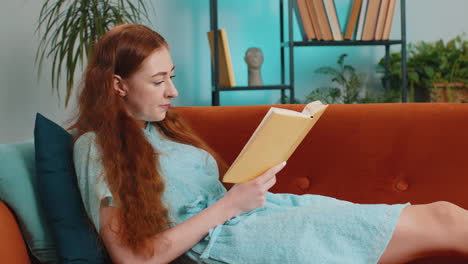 Young-woman-relaxing-interesting-book-turning-pages-smiling-enjoying-literature-taking-rest-on-sofa