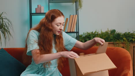 Happy-young-woman-shopper-unpacking-cardboard-box-delivery-parcel-online-shopping-purchase-at-home