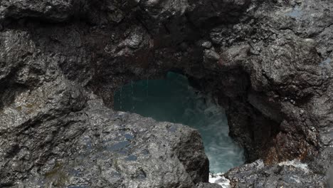 Volcanic-rock-hole-with-sea-water-waves-splashing-into-it,-close-up,-Tenerife