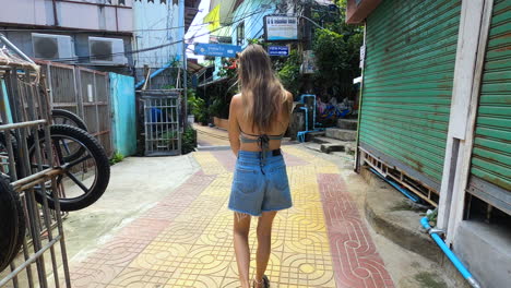 Rear-Of-A-Woman-Walking-Down-The-Old-Town-Street-In-Koh-Phi-Phi-Island-in-Andaman-Sea,-Phuket-Krabi,-Thailand