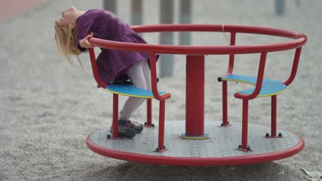 A-young-fair-haired-girl-rides-the-carousel-on-the-outdoor-playground