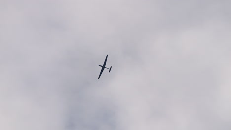Single-sailplane-soaring-in-cloudy-sky-and-making-turn,-tracking-shot