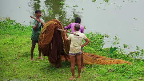 Rural-fishermen-lifting-fish-net-on-shoulder-after-fishing-at-a-lake-in-Bangladesh