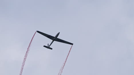 Glider-performing-challenging-maneuvers-and-leaving-red-smoke-trails-at-air-show