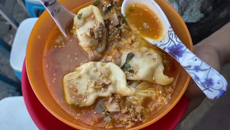 Top-down-shot-over-a-plate-of-steamed-momo-with-soup-served-in-a-yellow-bowl-been-served-at-a-roadside-food-stall