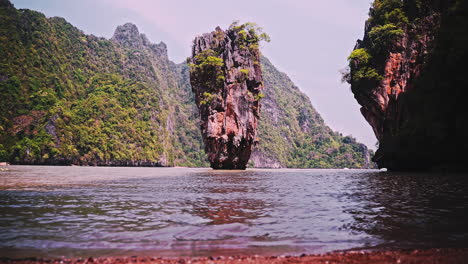 Rock-pillar-formation-close-to-shore-in-sea-bay-with-cliffs,-Thailand