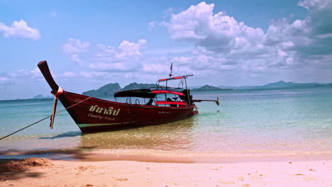 Cruising-touristic-wooden-motorboat-anchored-on-sand-beach-in-Thailand
