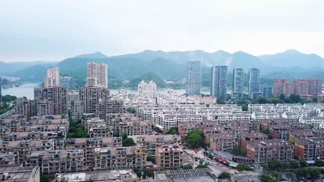 Tonglu-City-Skyline,-urban-scenery,-establishment-drone-shot,-aerial-ascending-movement-above-neighbourhood-apartments,-Tonglu-town-during-hazy-morning,-overview-in-Hangzhou,-Zhejiang-Province,-China