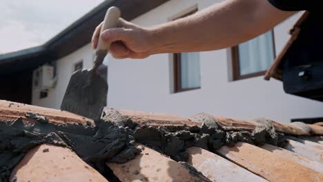 Builder-repairs-terracotta-tiled-wall-with-sand,-cement-and-trowel