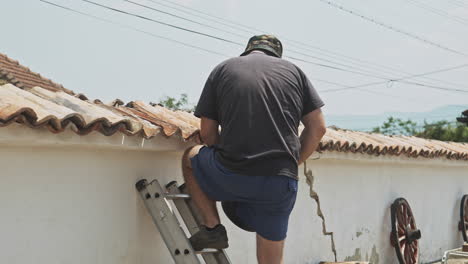 Man-on-ladder-repairs-terracotta-tiled-wall-with-cement-and-trowel-slow-motion