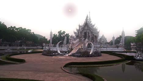 Thai-Wat-Rong-Khun-white-temple-with-ornate-sculptures-below-white-sky