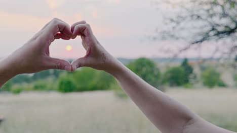 Hands-form-a-symbolic-love-heart-symbol-against-the-romantic-setting-sun
