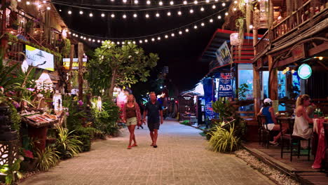 Couple-on-holiday-walking-in-streets-of-Railay-Bay-at-night,-Thailand