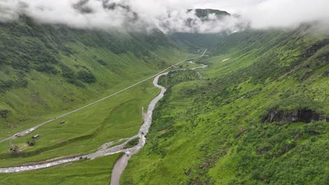 Lush-green-Kvassdalen-Valley-leading-to-Vikafjellet-mountain-pass-from-Voss-in-Western-Norway---Cinematic-summer-aerial-with-cloud-patches-around-mountain-tops