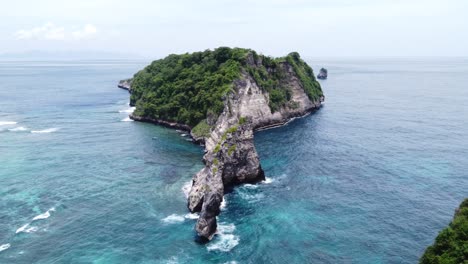 Limestone-island-eroded-away-off-of-atuh-Beach-Nusa-Penida-Indonesia,-aerial-establish