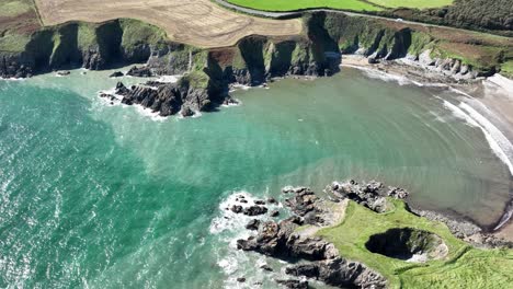 Ireland-Coast-the-sheltered-Kilmurrin-cove-sea-caves-and-blowholes-Copper-coast-Waterford-static-drone-shor