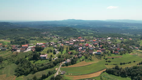 Una-Toma-De-Drone-De-Un-Pequeño-Pueblo-En-Eslovenia-Con-Colinas-Y-Bosques-Al-Fondo