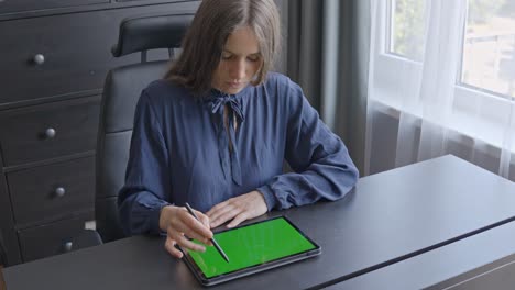 Mujer-De-Negocios-Enfocada-Trabajando-En-Su-Mesa-De-Oficina-Con-Tableta-De-Pantalla-Verde