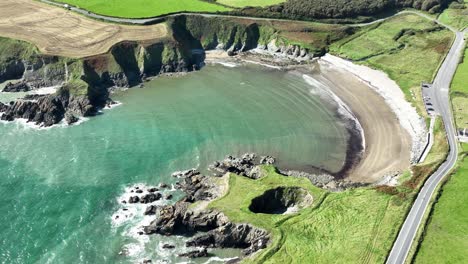 Coast-Ireland-aerial-static-of-The-Copper-Coast-Road-winding-its-way-past-Kilmurrin-Cove-and-its-blowhole-at-Waterford-on-a-summer-day