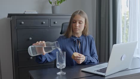 In-office,-woman-pouring-water-from-glass-carafe-into-small-glass