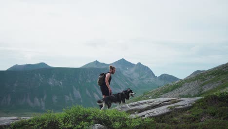 Wanderer-Mit-Rucksack,-Der-Die-Leine-Des-Siberian-Husky-Hält,-Während-Er-Auf-Den-Salberget-Hügel-In-Norwegen-Geht