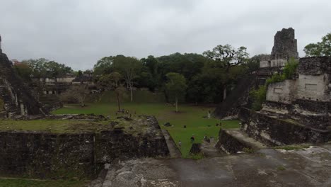 Pan-across-Tikal-central-plaza-with-Grand-Jaguar-Temple,-Mayan-ruins