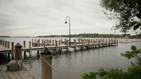 Wide-push-in-shot-past-a-tree,-revealing-a-wooden-boat-dock-with-multiple-bays