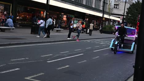 Blue-rickshaw-within-Oxford-Street,-looking-for-tourists,-London,-United-Kingdom