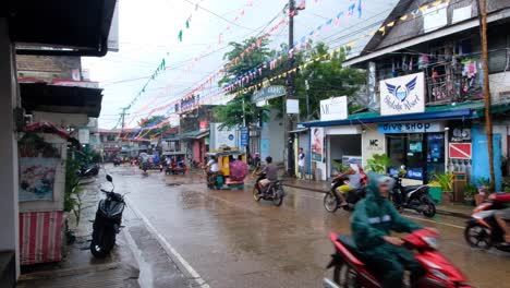 Busy-Filipino-streets-of-motorbikes-and-tricycle-taxis-during-wet,-rainy-day-in-Coron-Town,-Palawan-in-the-Philippines,-Southeast-Asia