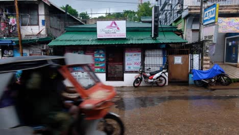 Tricycles-and-motorbikes-on-wet-streets-during-heavy-rain-in-Coron-Town,-Palawan-in-the-Philippines,-Southeast-Asia