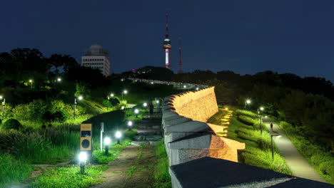 Nachtzeitraffer-Von-Menschen,-Die-Entlang-Der-Hanyangdoseong-Stadtmauer-Von-Seoul-Im-Namsan-Park-Spazieren,-Mit-Ikonischem-Blick-Auf-Den-Seoul-Tower-–-Dynamisches-Herauszoomen
