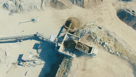 loaded-truck-driving-into-dusty-crushed-stone-quarry-gravel-pit,-wide-aerial-establishment-shot