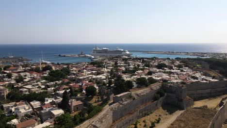 Drone-dolly-over-medieval-wall-and-ancient-Rhodes-old-town-to-modern-cruise-ship