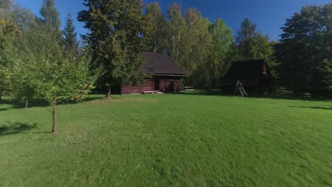 Historic-wooden-rural-houses-with-beautiful-green-lawns-and-trees-in-a-Polish-open-air-museum