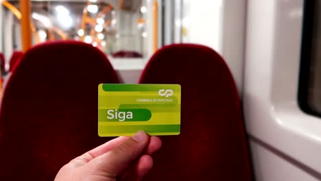 Male-hand-holding-Portuguese-green-train-card-inside-of-an-empty-train-passenger-wagon
