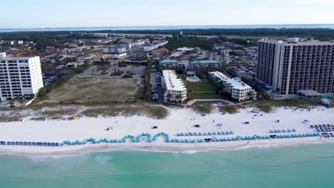 Beach-Aerial-Destin-Florida-Luxurious-tropical-beach-resort-or-hotel-with-beach-service-colorful-umbrellas-on-the-beachfront,-Aerial-view-with-panning-left-motion-of-drone-camera-video