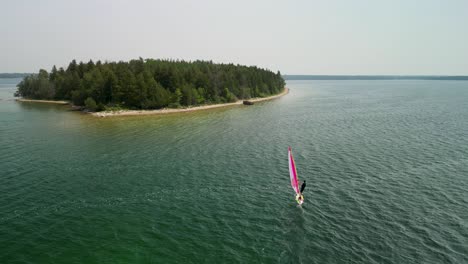 Aerial-orbit-of-windsurfer-going-to-shoreline,-Lake-Huron,-Michigan
