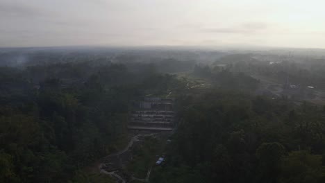 Panorama-drone-shot-of-foggy-landscape-over-asian-waterfall-during-mystic-sunrise