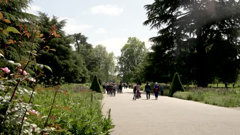 Visitors-Walking-Along-Path-Exploring-Kew-Gardens-On-Summers-Day