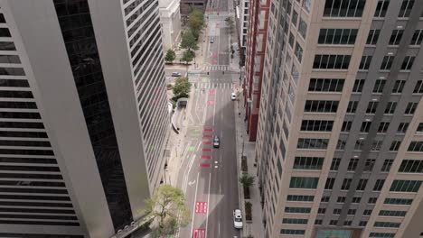 Aerial-top-down-of-traffic-on-road-in-Denver-city,-flying-close-to-skyscrapers-surroundings