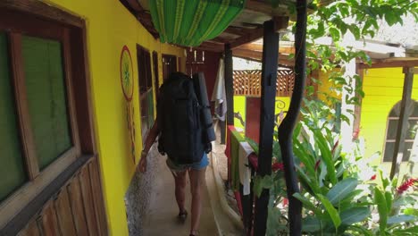Slo-mo:-Woman-with-large-backpack-walks-down-colorful-hostel-passage