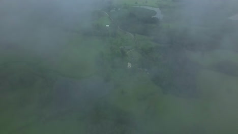 Aerial-Tilt-Up-Shot-Through-Patches-of-Fog-Like-Clouds-Looking-Down-at-the-Green-Landscape-in-Latvia