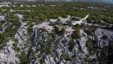 A-captivating-drone-view-of-viewpoint-near-Paklenica,-Croatia's-Velebit-mountains,-featuring-cliffs,-cars,-and-lush-Mediterranean-flora-under-the-summer-sun
