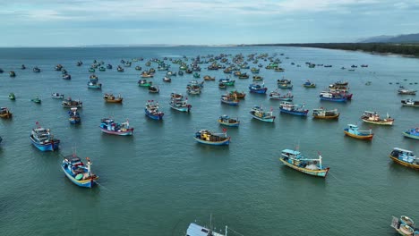 Drone-view-hundreds-of-fishing-boats-nailing-on-La-Gan-beach-of-Binh-Thuan,-central-Vietnam