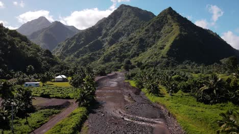 A-washed-out-and-eroded-river-bed-leads-into-a-spectacular-valley-with-volcanic-mountain-peaks-in-Tahiti