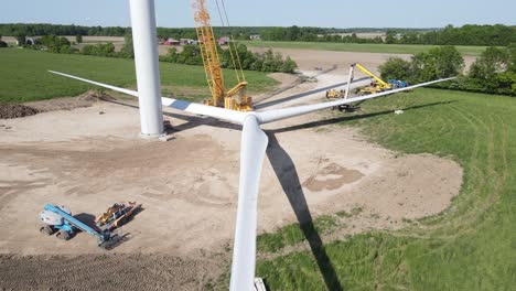 Wind-turbine-blades-ready-to-be-lifted-on-top,-aerial-ascend-view