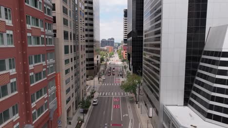 Drone-flying-in-Denver-downtown-between-city-skyscrapers,-sunny-day-in-United-States