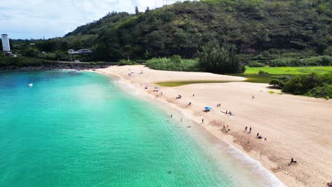 Aerial-along-Waimea-beach,-sunbathers,-swimmers,-Oahu,-Hawaii