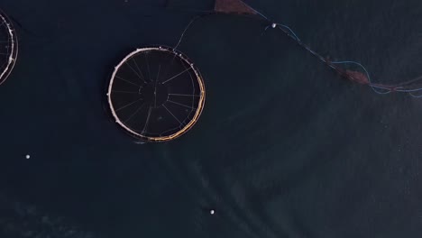 Bird's-eye-view-drone-shot-of-a-fish-farm,-a-fishing-boat-and-a-well-boat